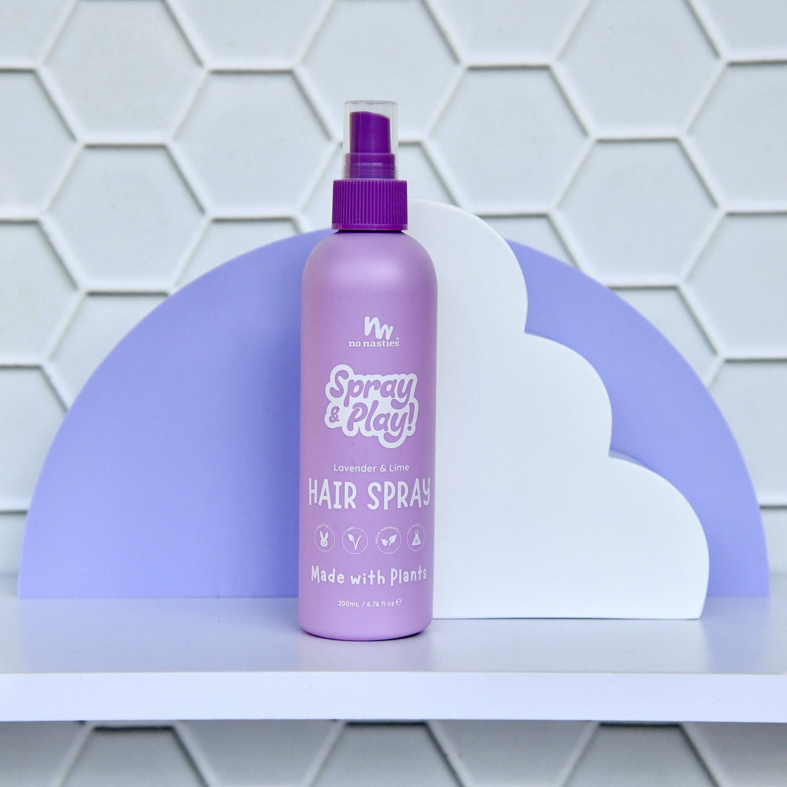 Purple hair spray bottle on a white shelf with a geometric patterned wall in the background