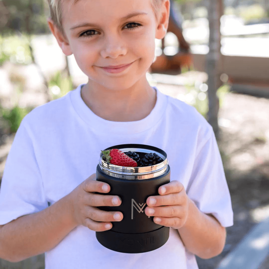 Little boy holding montii nz insulated food jar with fruit inside